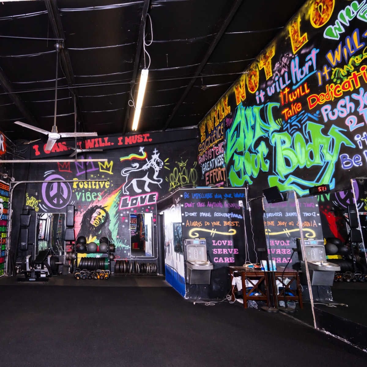 A vibrant gym interior adorned with colorful graffiti and motivational phrases on the walls.