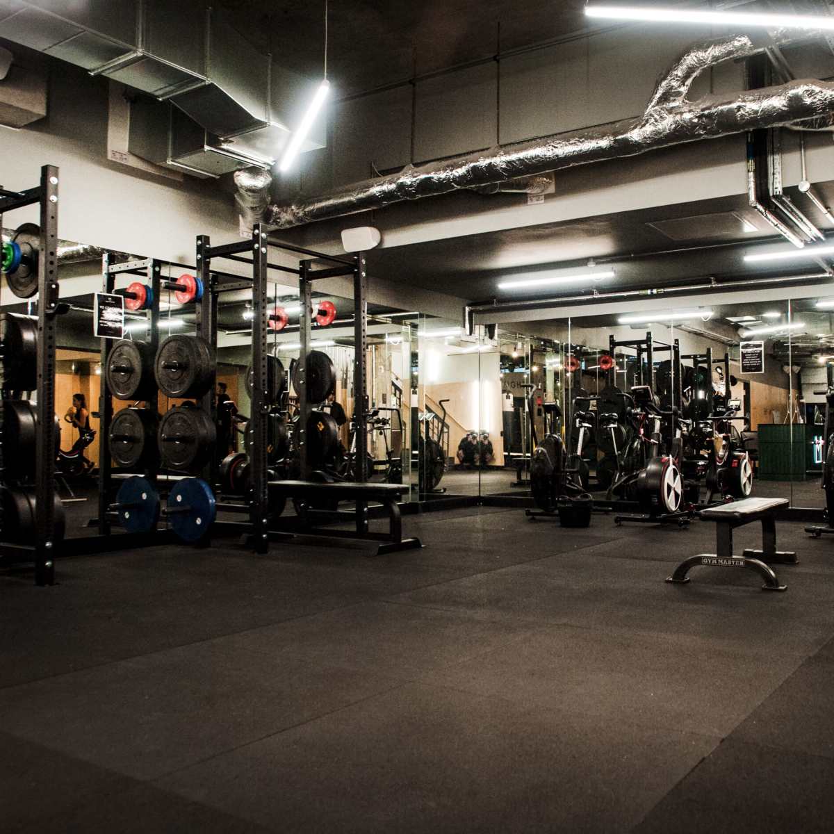 A spacious gym equipped with various weightlifting and cardio machines, including benches, barbells, and exercise bikes.