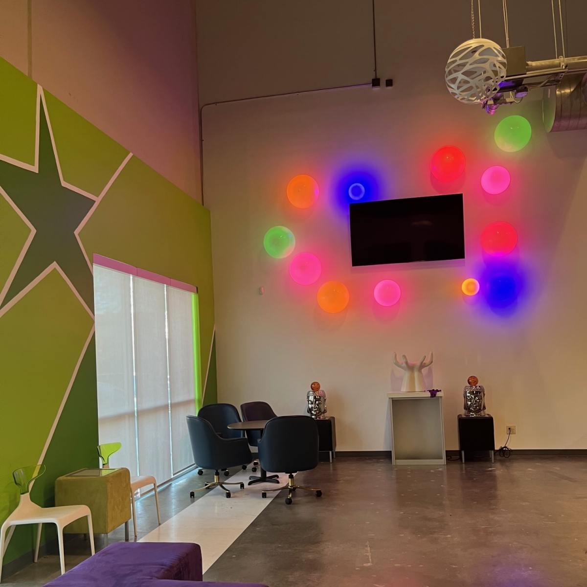 A modern lounge area featuring colorful wall decorations, a wall-mounted screen, and contemporary seating arrangements.