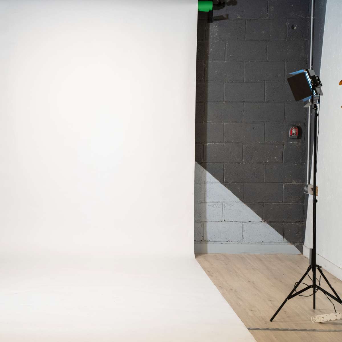 A photography studio features a white backdrop and two lighting setups on either side.