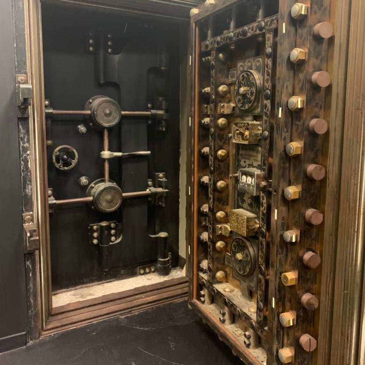 An ornate, vintage safe with intricate dials and mechanisms, partially open to reveal its inner workings.