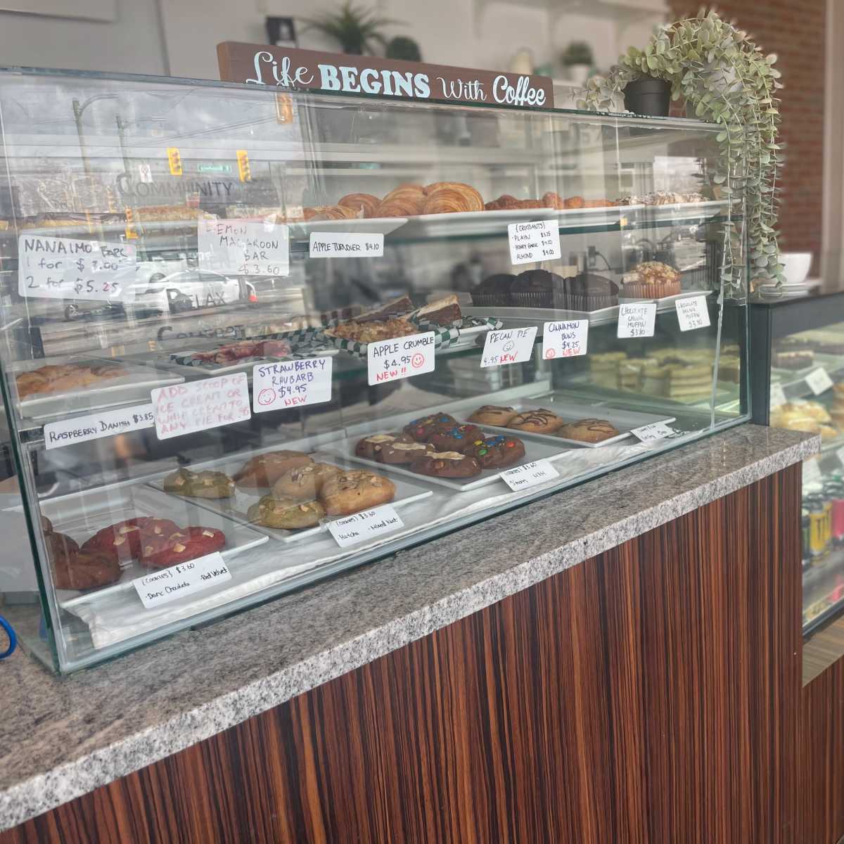 A café display case filled with various pastries and baked goods, alongside a refrigerated section with drinks.