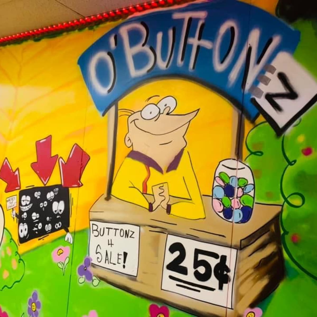 A colorful mural depicts a cartoon character selling buttons at a stand labeled "O'Buttonz" for 25 cents.