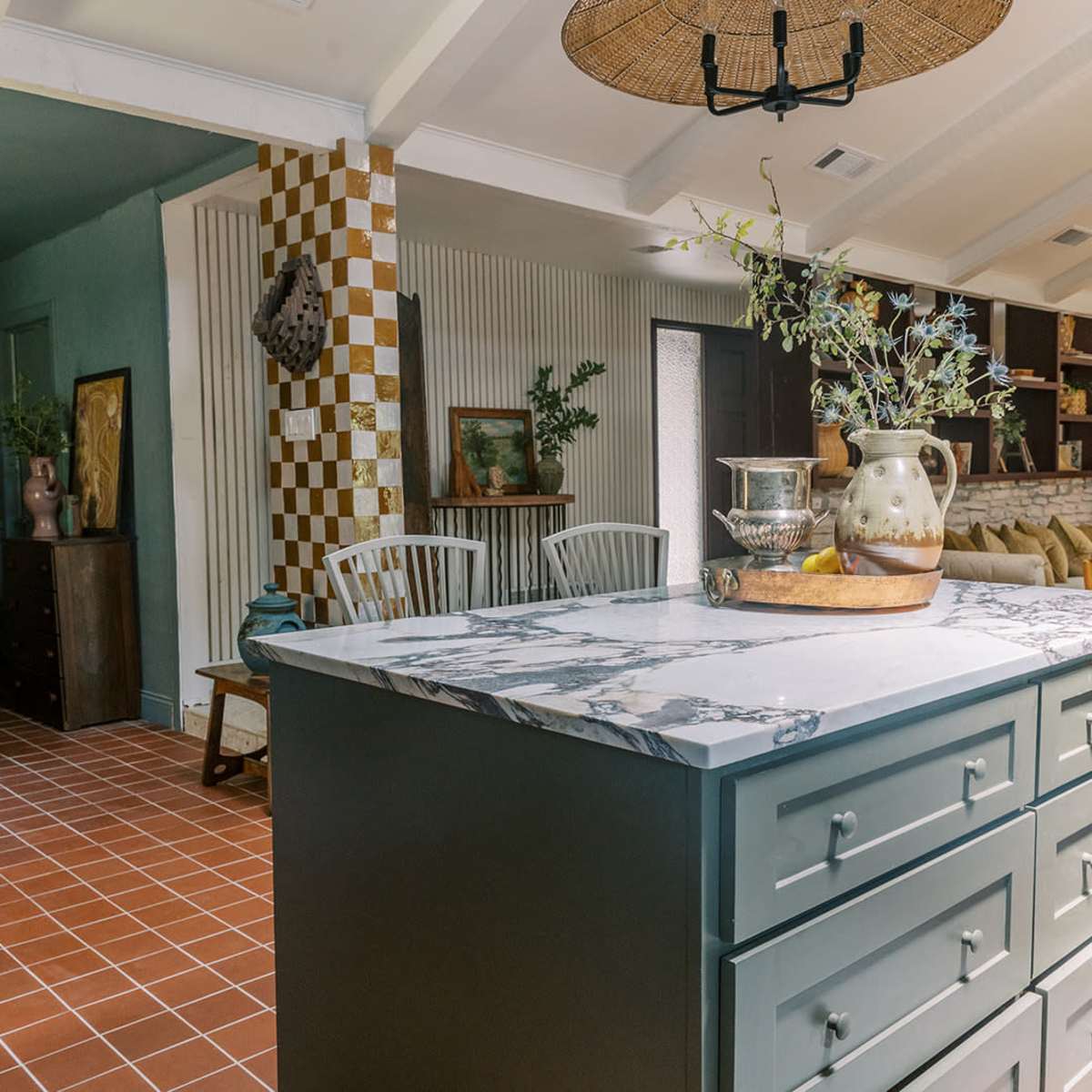 A modern kitchen with a patterned tile floor, a marble-topped island, and an open layout leading to a living area with decorative accents.