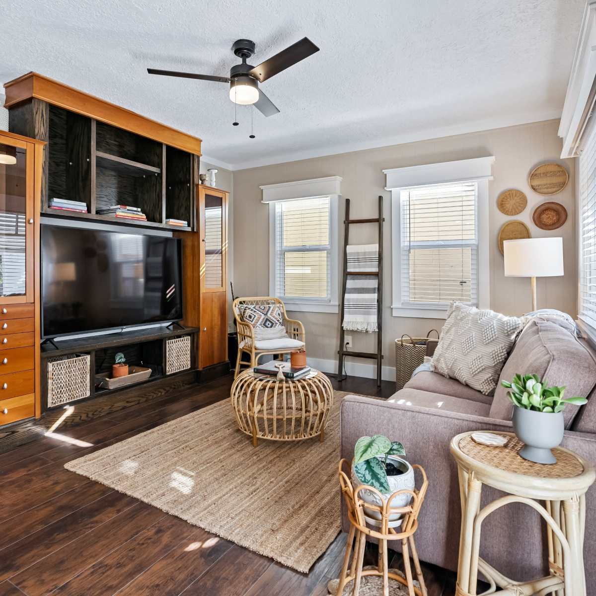 The living room features a television stand with storage, a sofa, a rattan coffee table, and decorative wall elements.