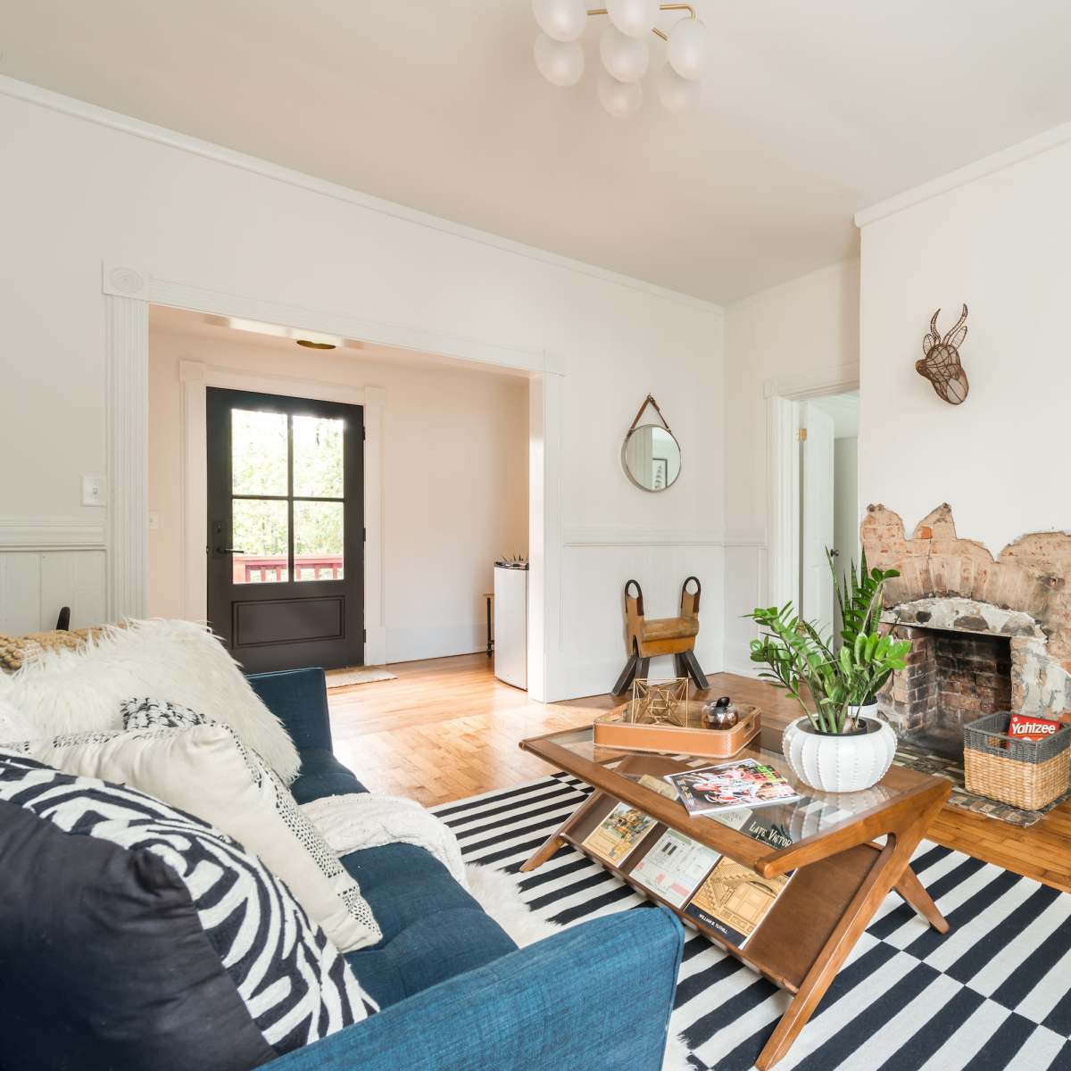 The living room features a blue sofa, a wooden coffee table on a striped rug, a brick fireplace, and a wall-mounted television.