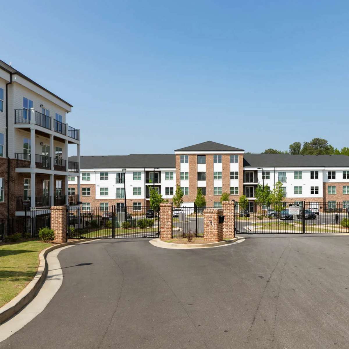 A gated residential complex with several three-story buildings and a paved roadway leading into the entrance.