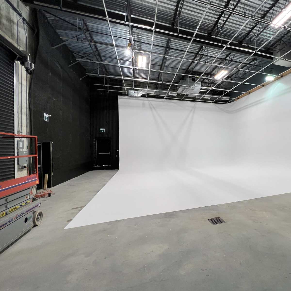 A spacious photo studio with a seamless white backdrop and a concrete floor.