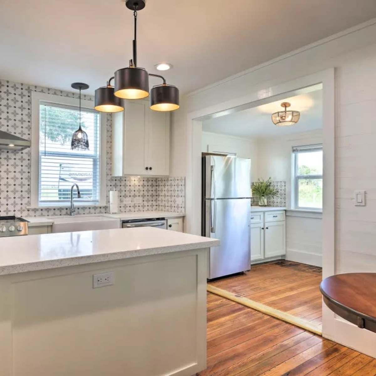 A modern kitchen featuring a central island, stainless steel appliances, and patterned backsplash tiles.