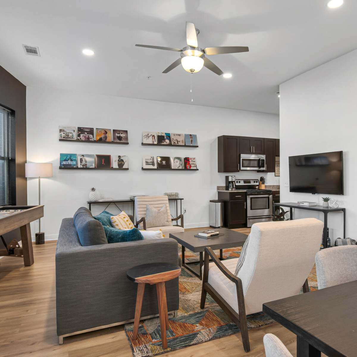 A modern living room and dining area with a comfortable sofa, wooden dining table, and a wall-mounted television.