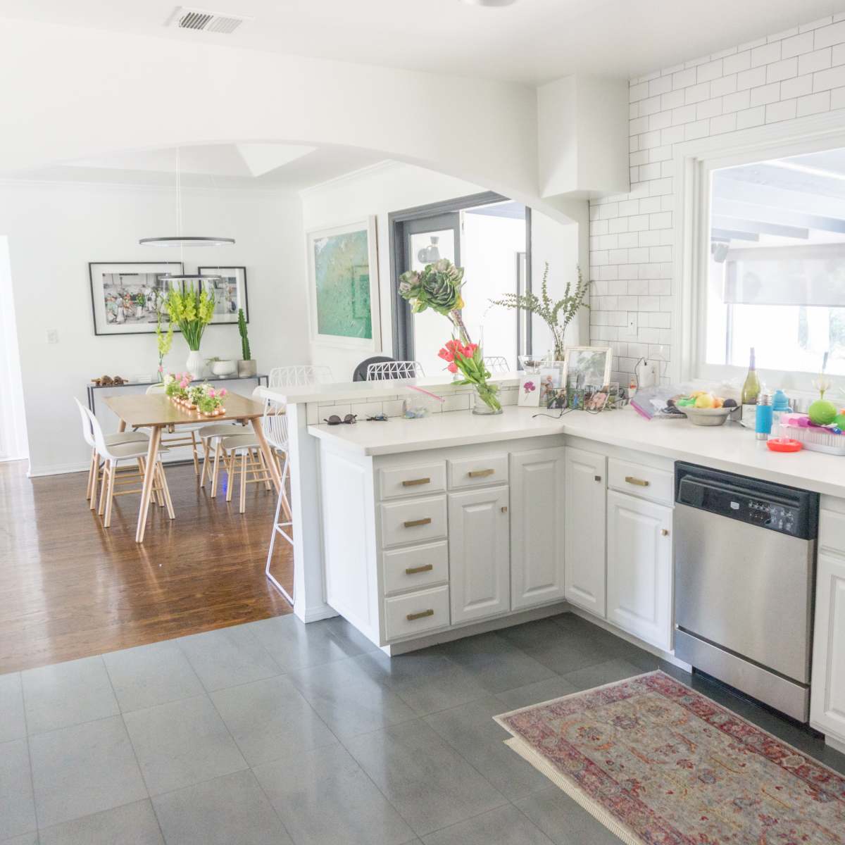 A spacious kitchen with white cabinetry, a tiled backsplash, and stainless steel appliances, leading into a bright dining area.