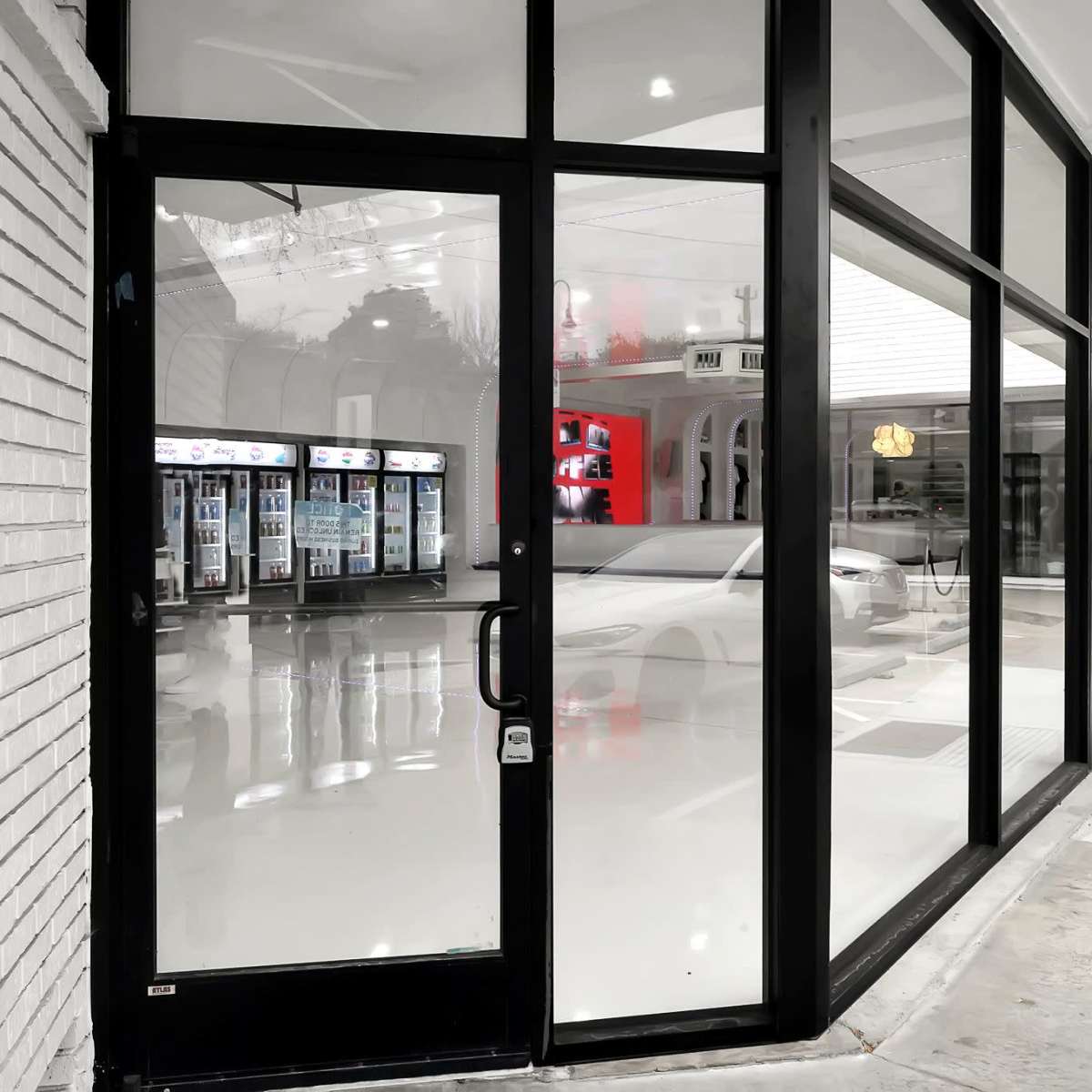 A modern storefront with large glass windows and a polished floor, featuring vending machines visible inside.