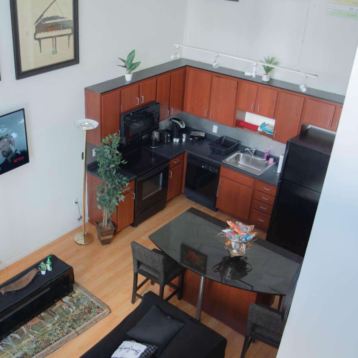 A modern, open-concept kitchen and living area with a television featuring a scene from a show, surrounded by furniture and decor.