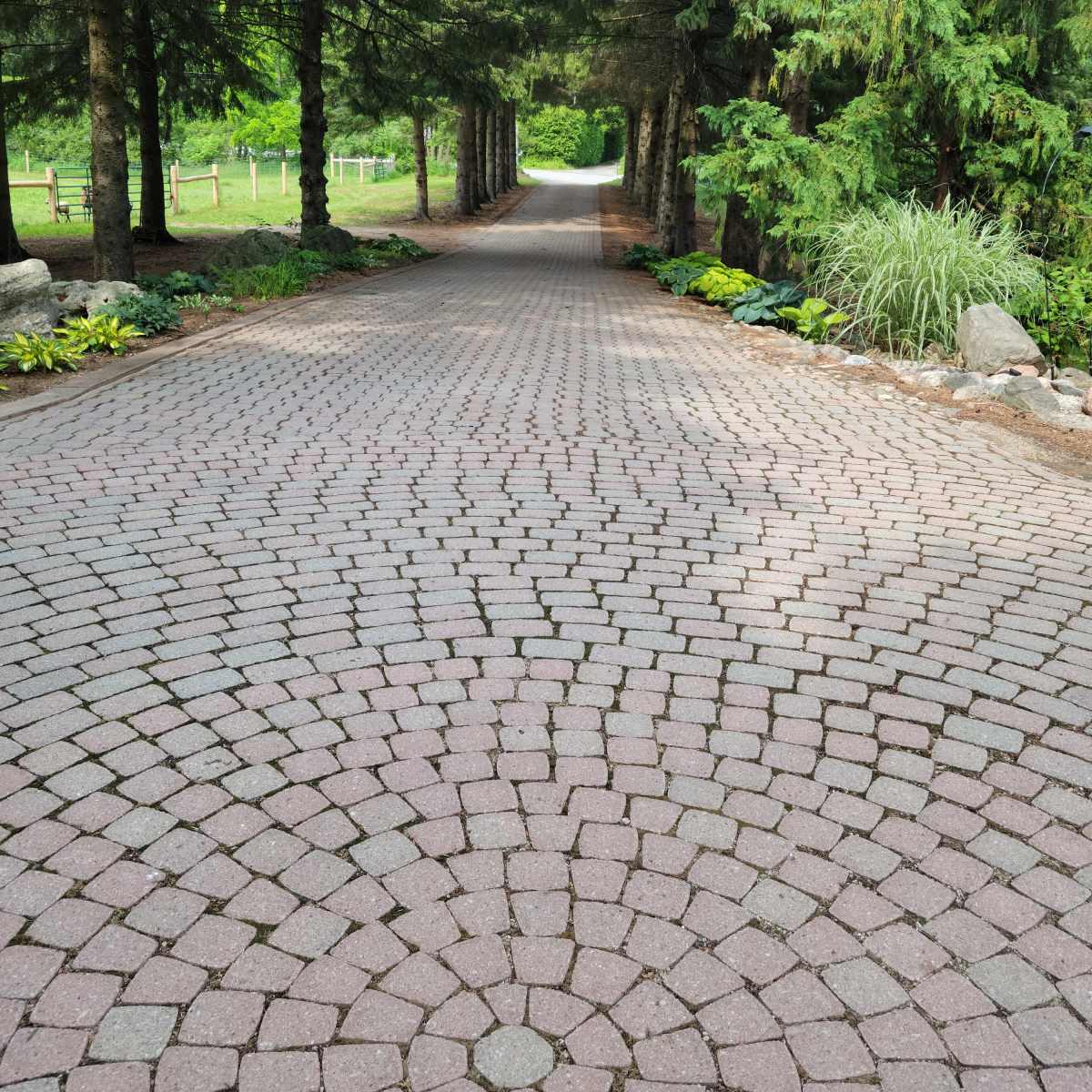 A brick pathway lined with trees leads toward a distant opening in a lush, green landscape.