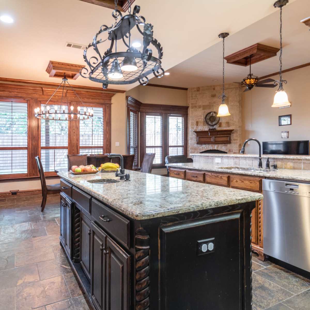 The kitchen features dark wooden cabinetry, a large granite island, and multiple windows for natural light.