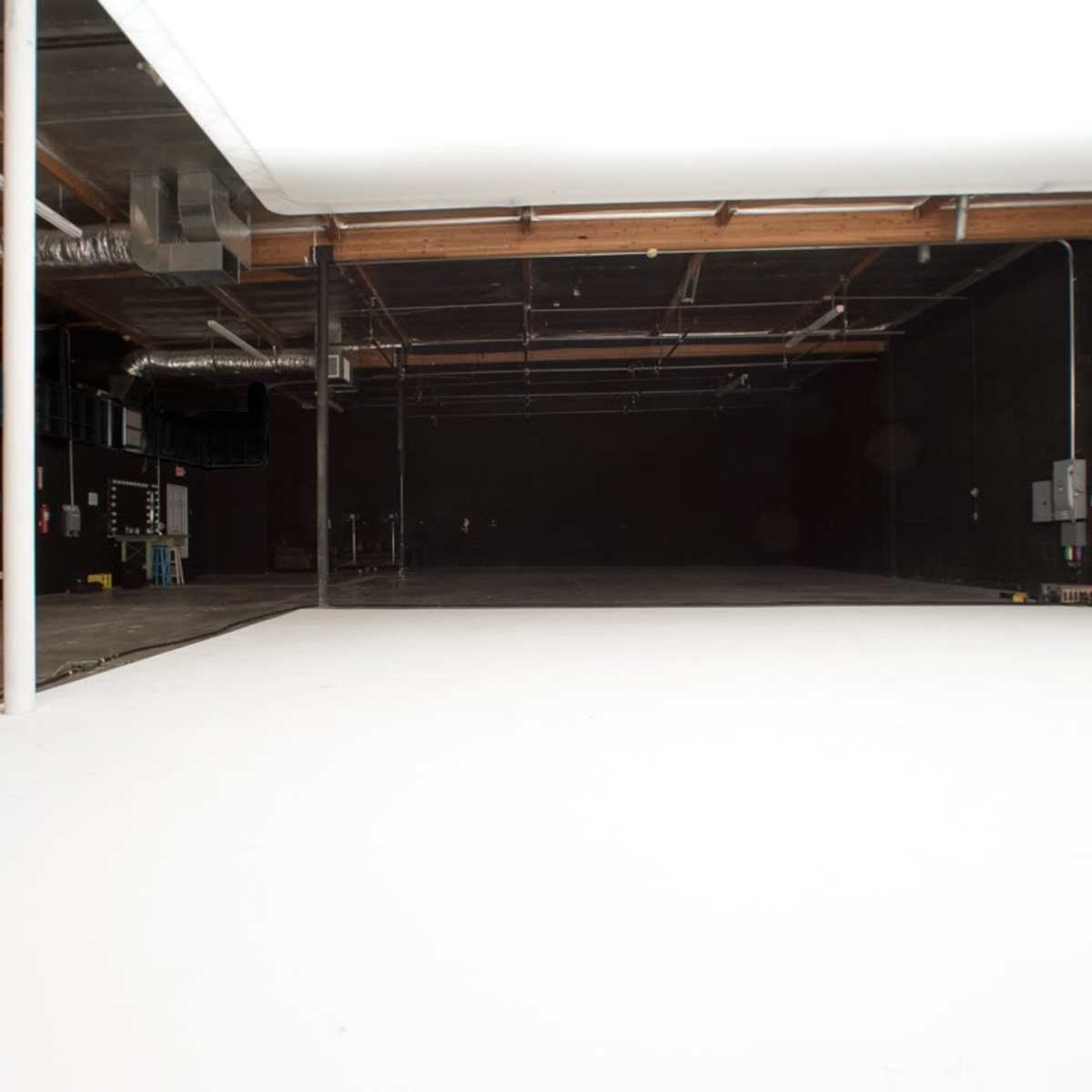 An empty photography studio features a white backdrop and dark walls.