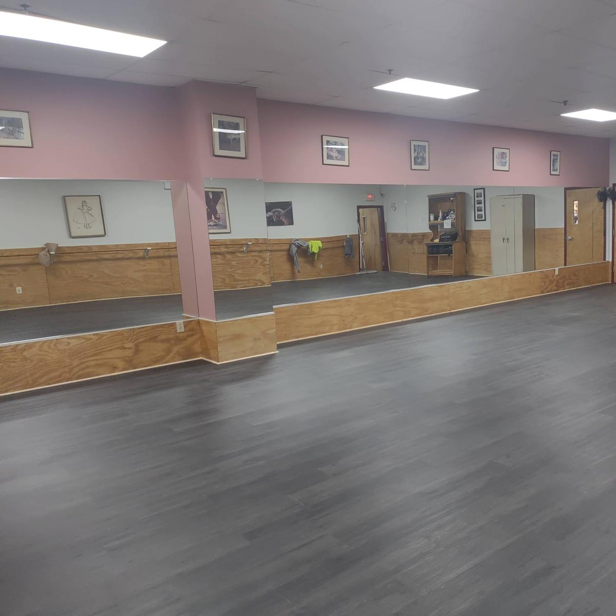 A spacious dance studio with mirrored walls and a wooden floor.