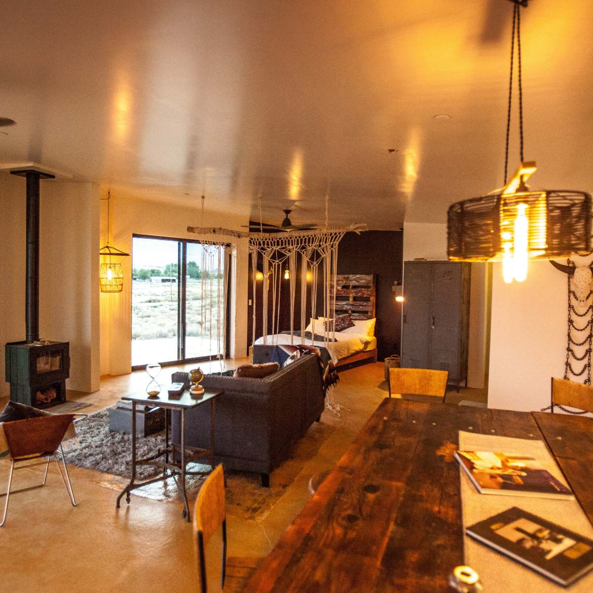A modern, open-concept living space featuring a seating area with a sofa, a dining table, and large windows that overlook a landscape.
