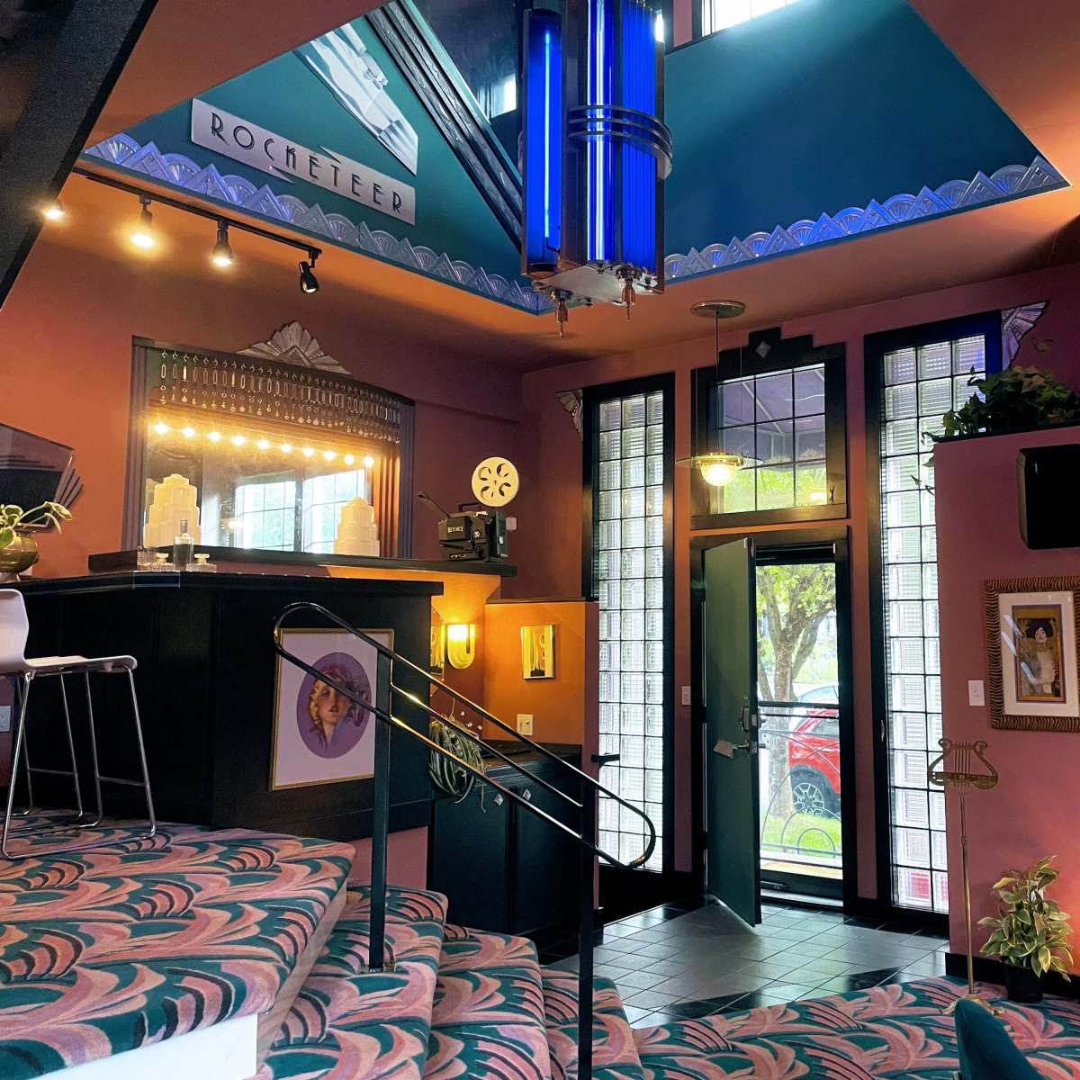 An interior space with colorful walls, a staircase leading to a raised area, and large windows that open to an outdoor view.