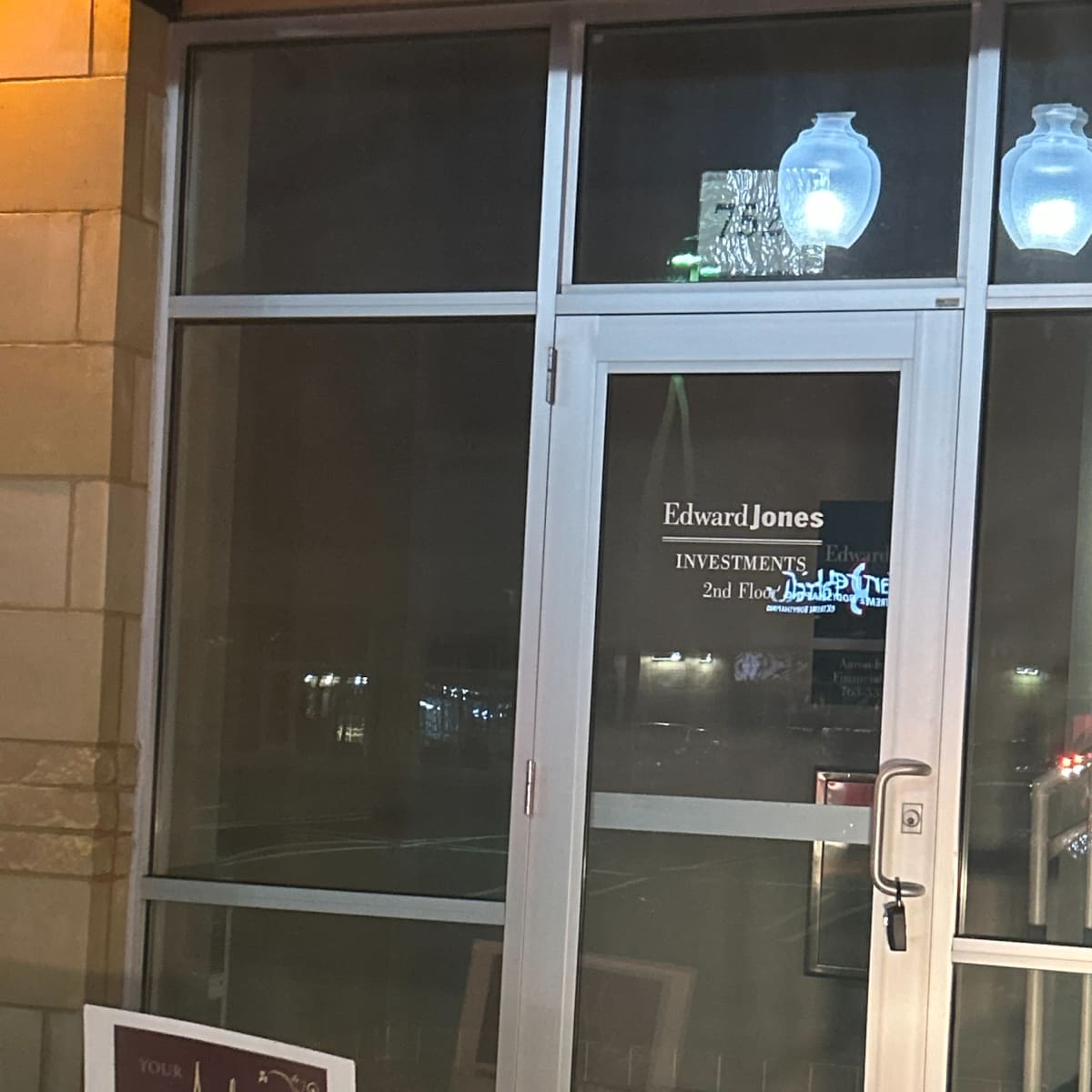 The entrance of an Edward Jones investment office located on the second floor, with a promotional sign for a photography business placed nearby.