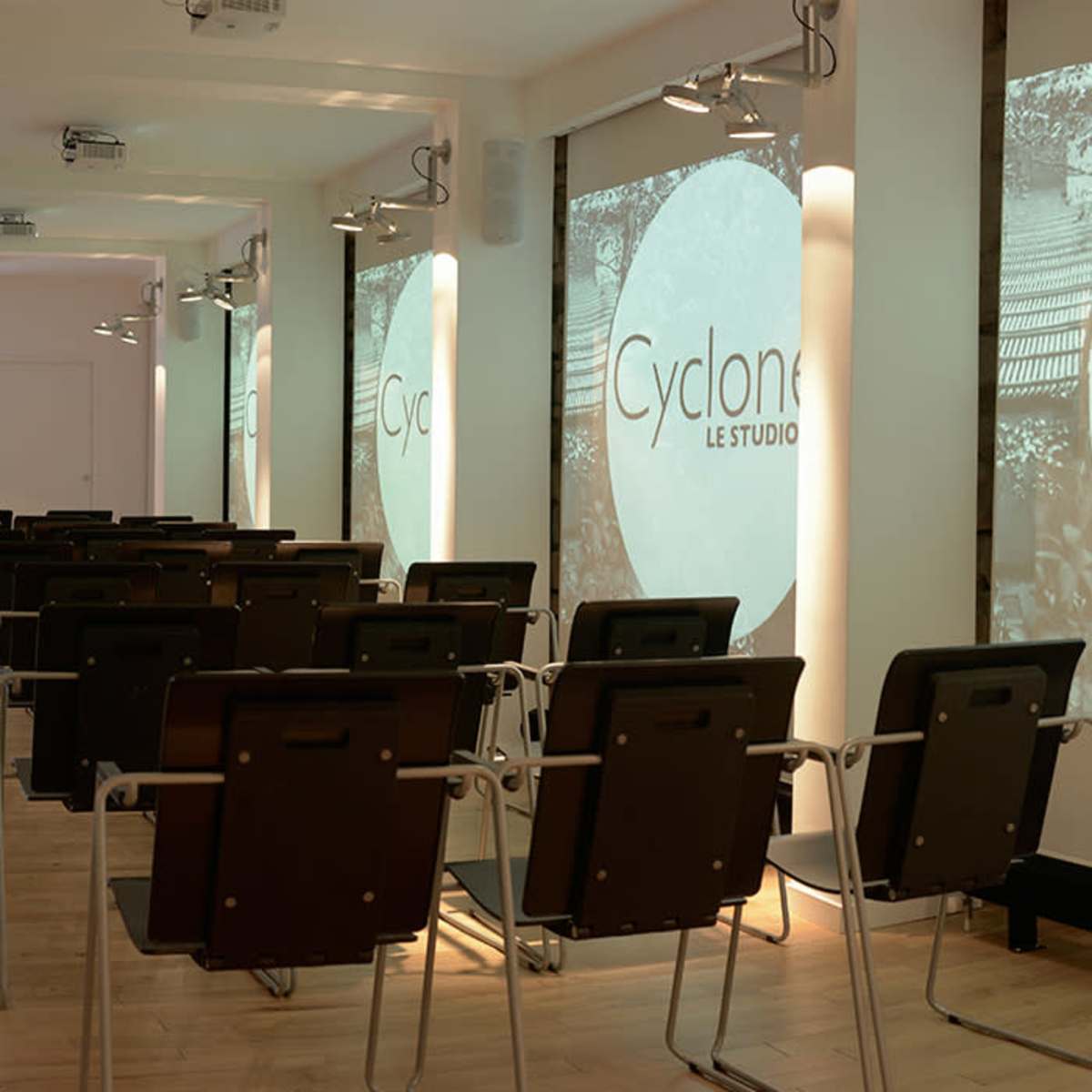 A modern conference room with rows of chairs facing a projector screen displaying the word "Cyclone."