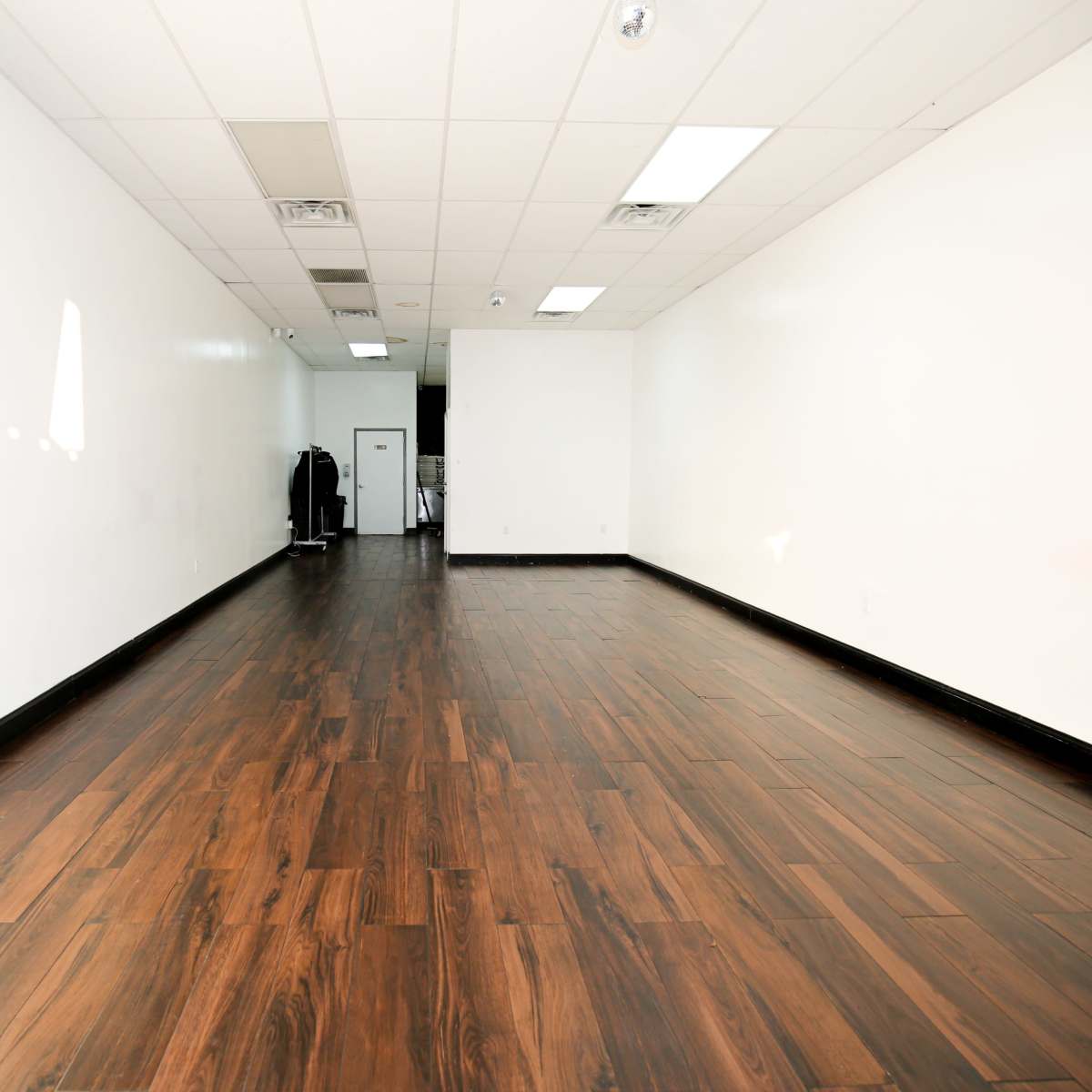 A spacious, empty retail area with wooden flooring and white walls.