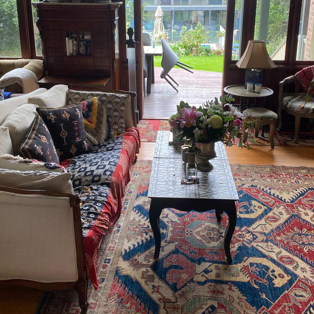 A living room filled with various seating arrangements and decor leads to a patio area with a pool visible through the open door.