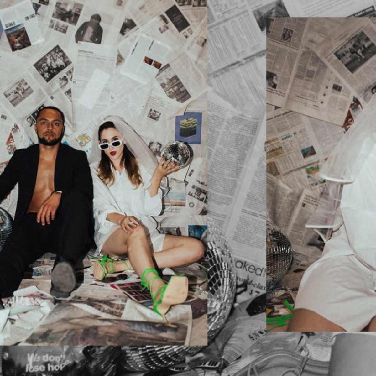 A man and a woman sit against a backdrop of newspapers, with the woman wearing sunglasses and holding a disco ball.
