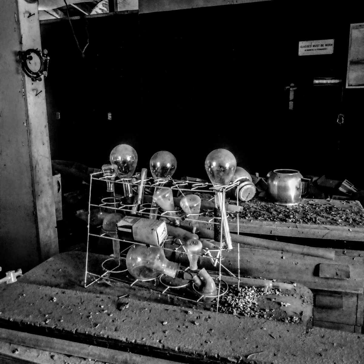 A disorganized assembly of glass light bulbs on a dusty rack in an abandoned space.