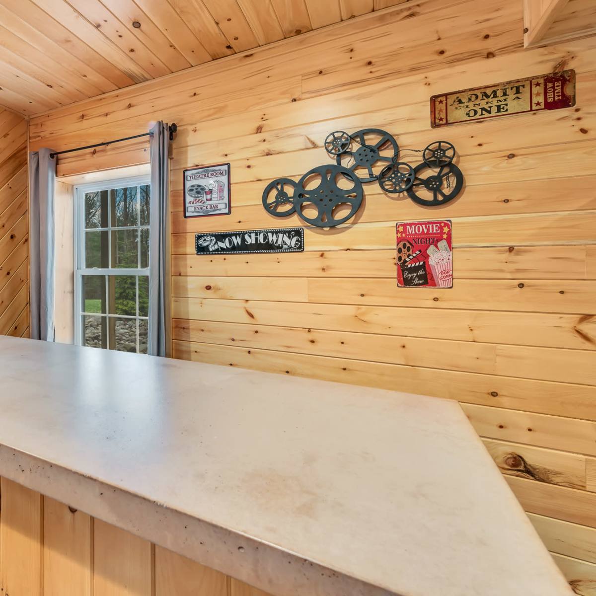 A wooden bar area with a concrete countertop, featuring vintage movie-themed decorations on the walls.