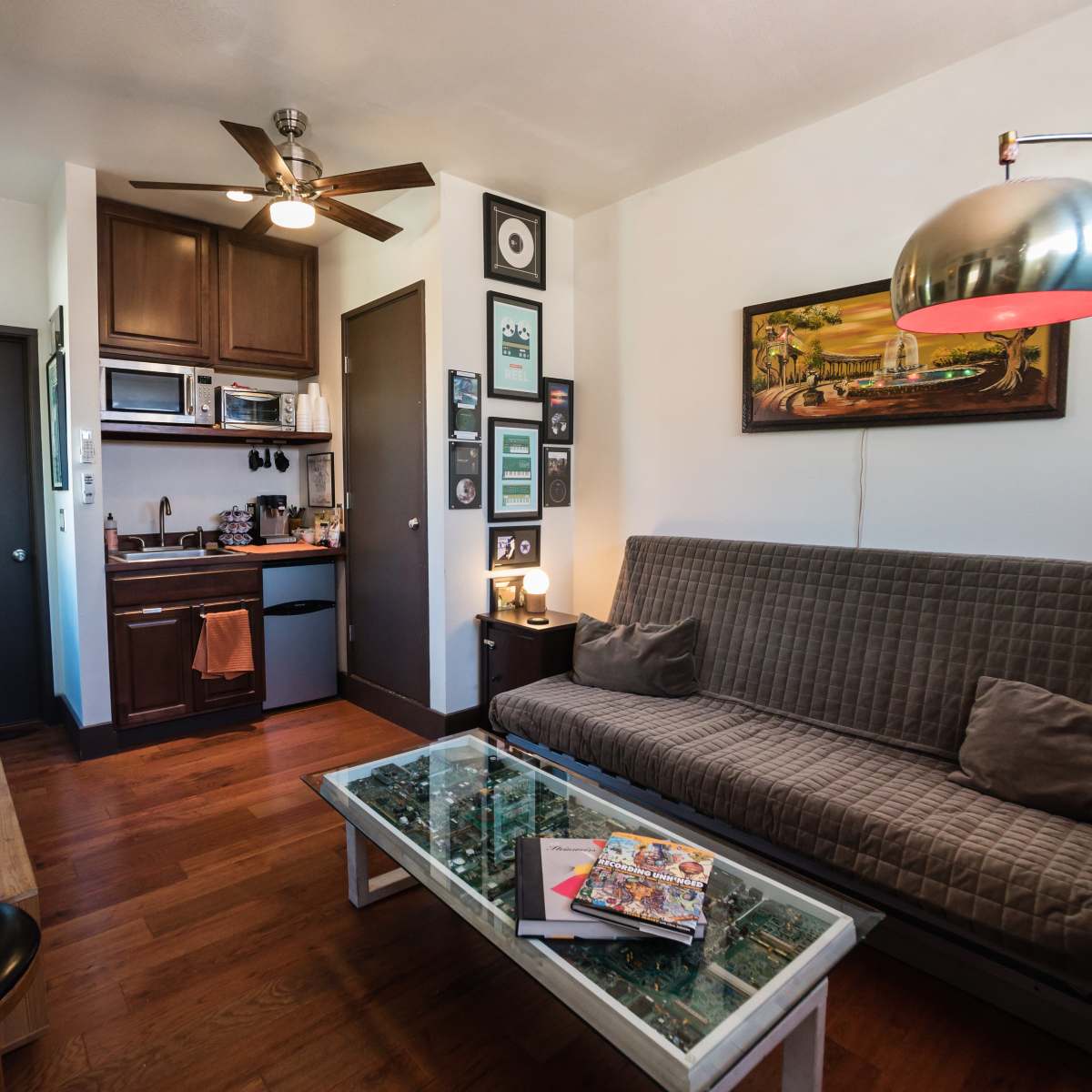 A small living space with a futon, a kitchenette, and various decorations on the walls.