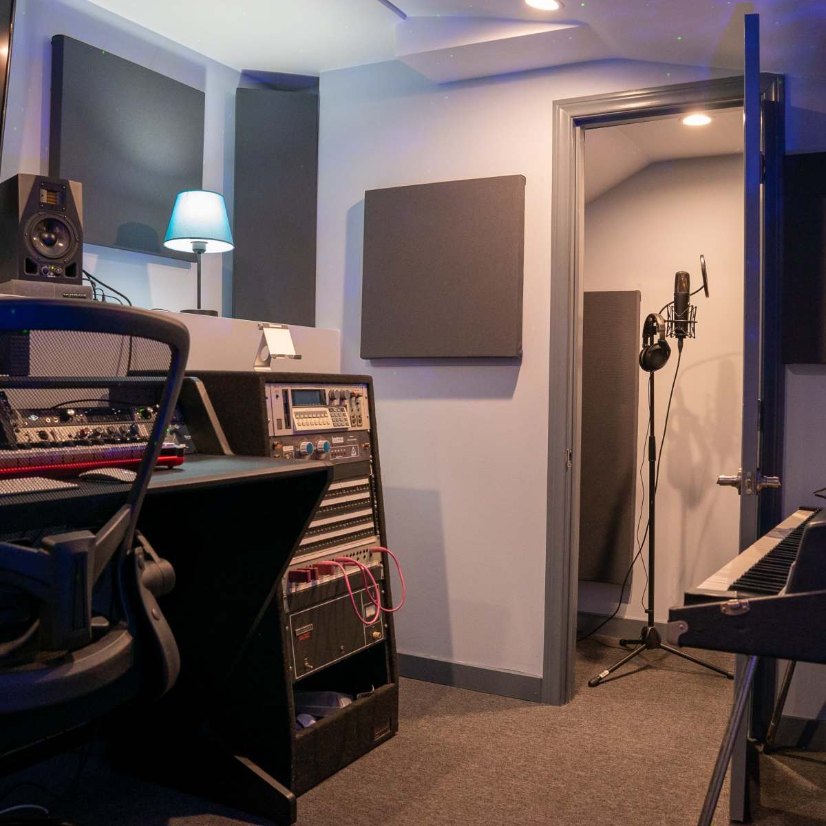 A small music studio with recording equipment, a keyboard, and a microphone set up in a corner.