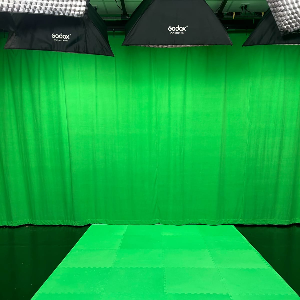 A green screen setup with a green floor mat and overhead lighting.