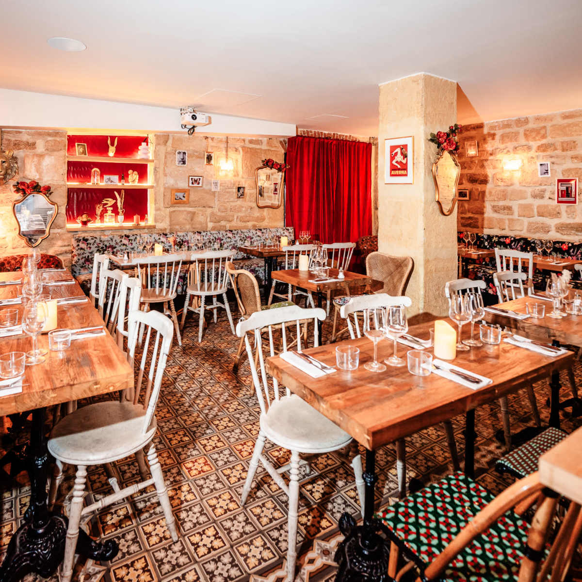 A restaurant interior with wooden tables, white chairs, patterned flooring, and decorative elements on the walls.