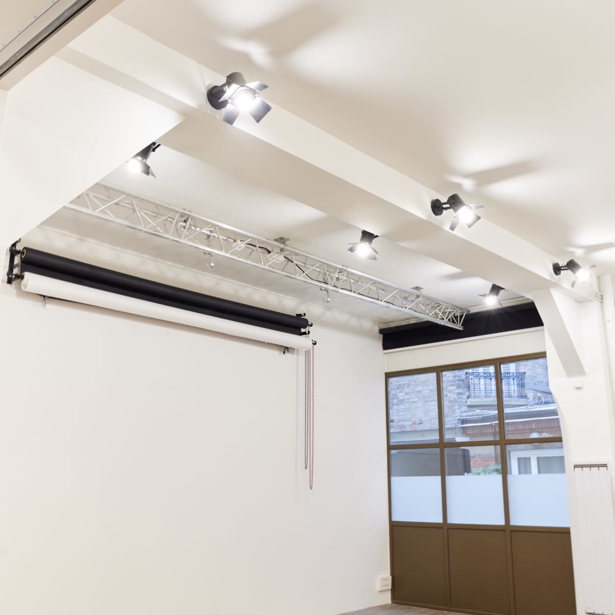 A spacious, well-lit studio with ceiling lights and a large window.