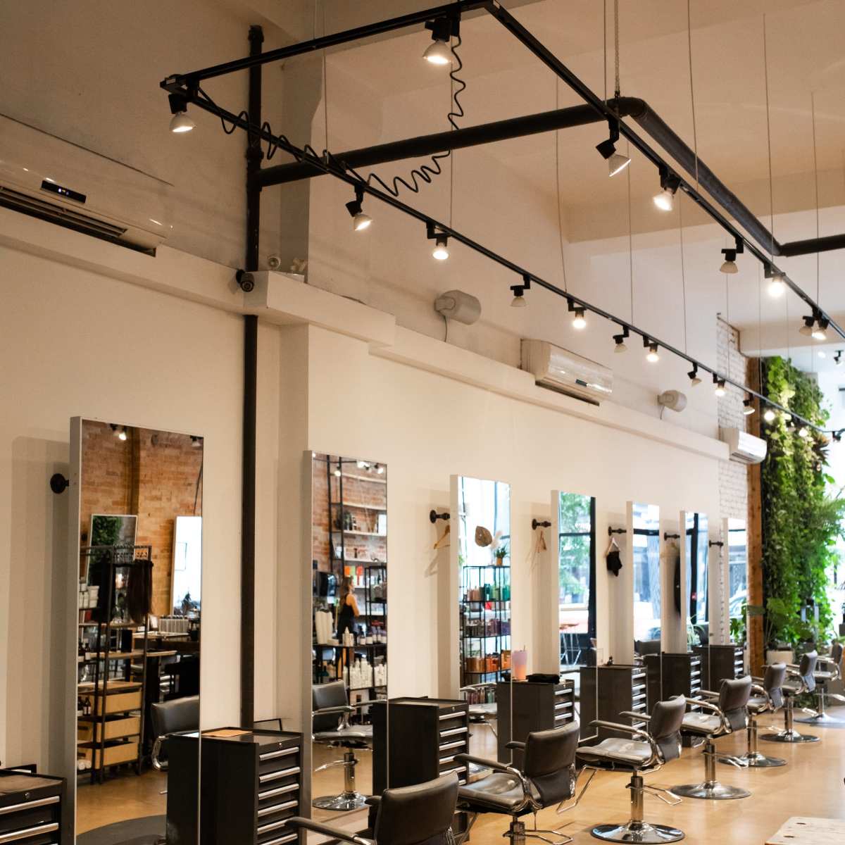 A modern hair salon featuring multiple styling stations with mirrors and adjustable salon chairs arranged in a spacious layout.