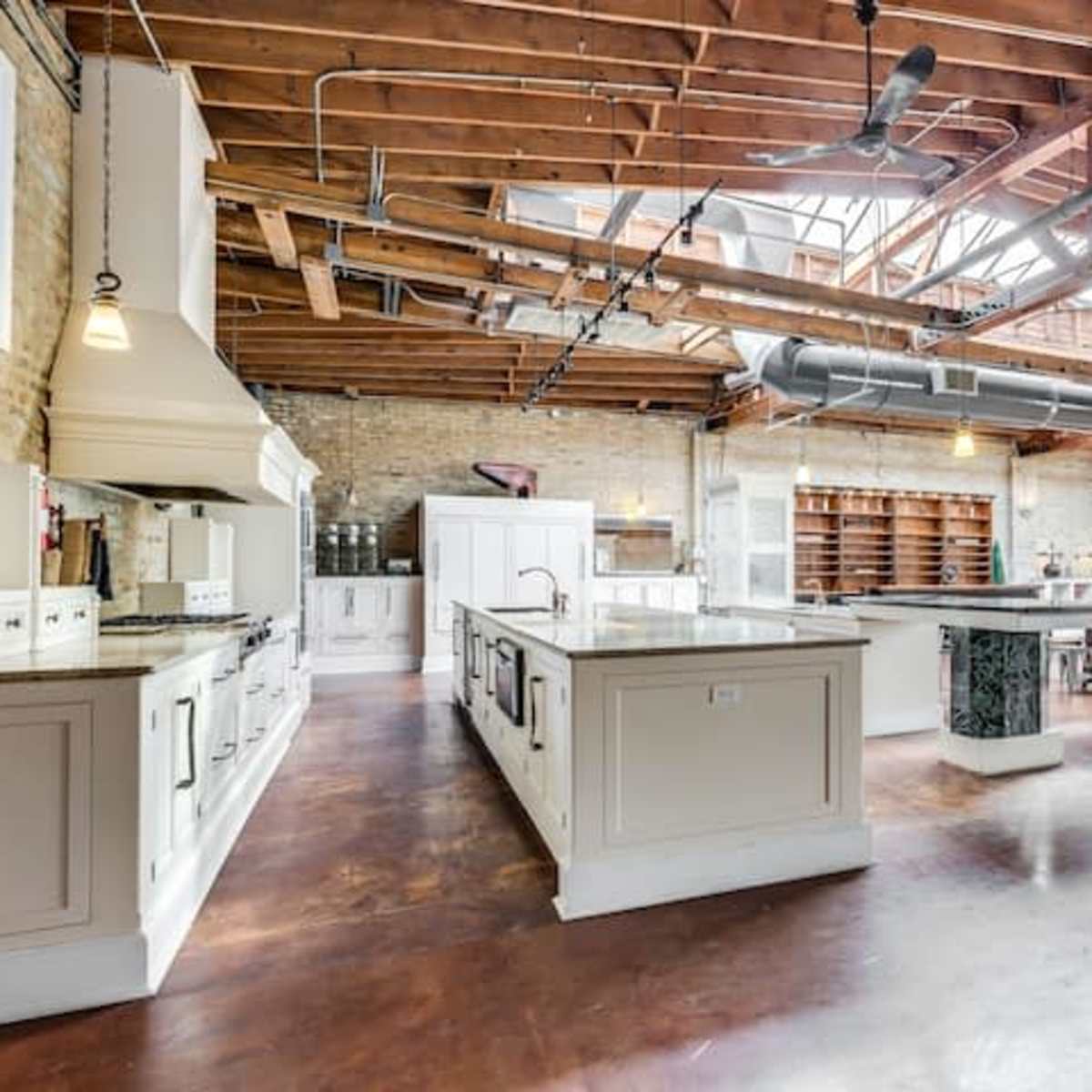 A spacious kitchen area with wooden beams, an island in the center, and ample cabinetry along the walls.