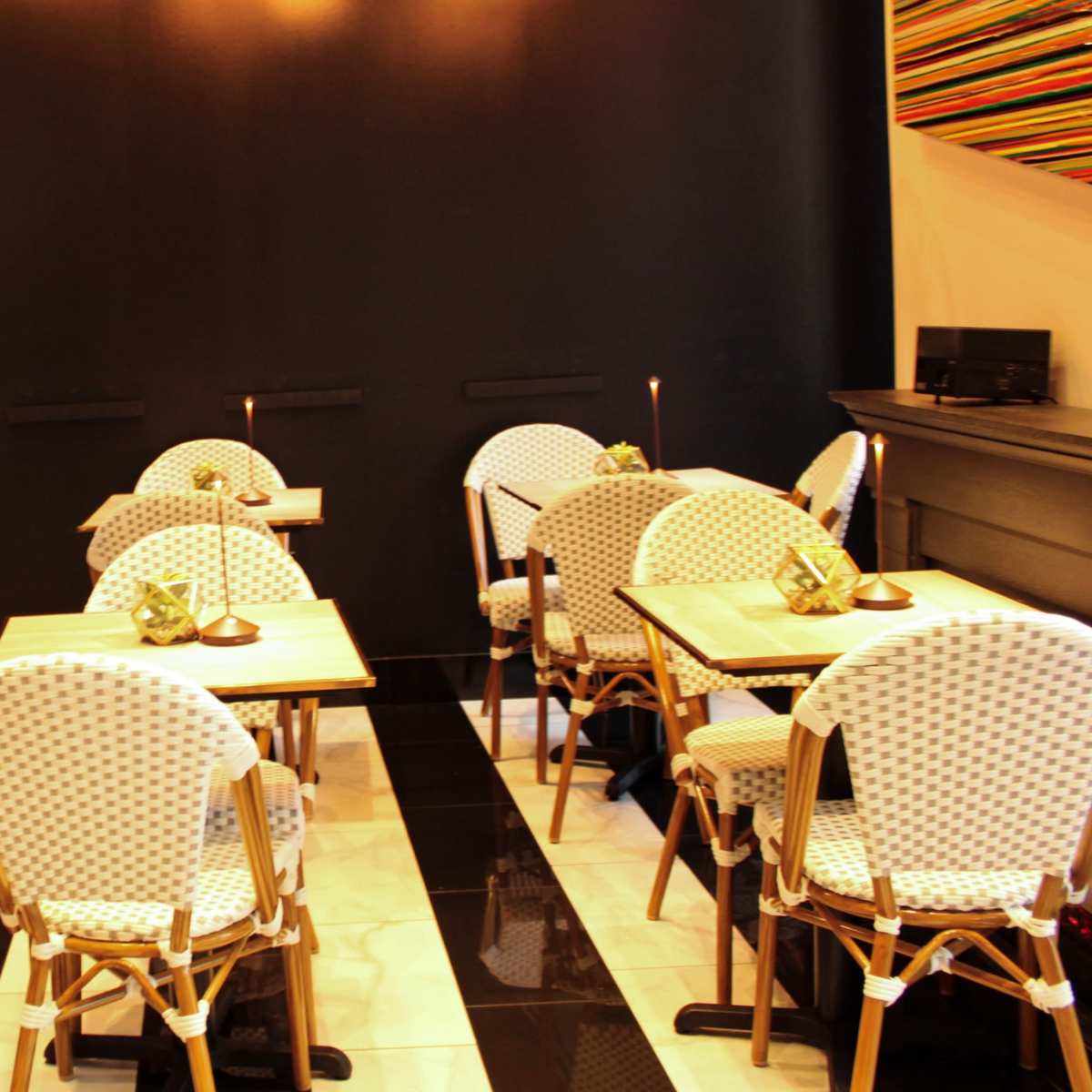 A cozy restaurant interior with several tables and patterned chairs arranged neatly on a tiled floor.
