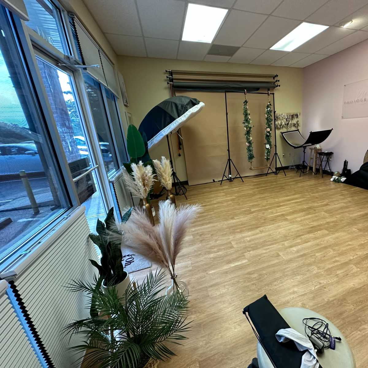 A photography studio with various lighting equipment, backdrops, and decorative elements arranged on a wooden floor.