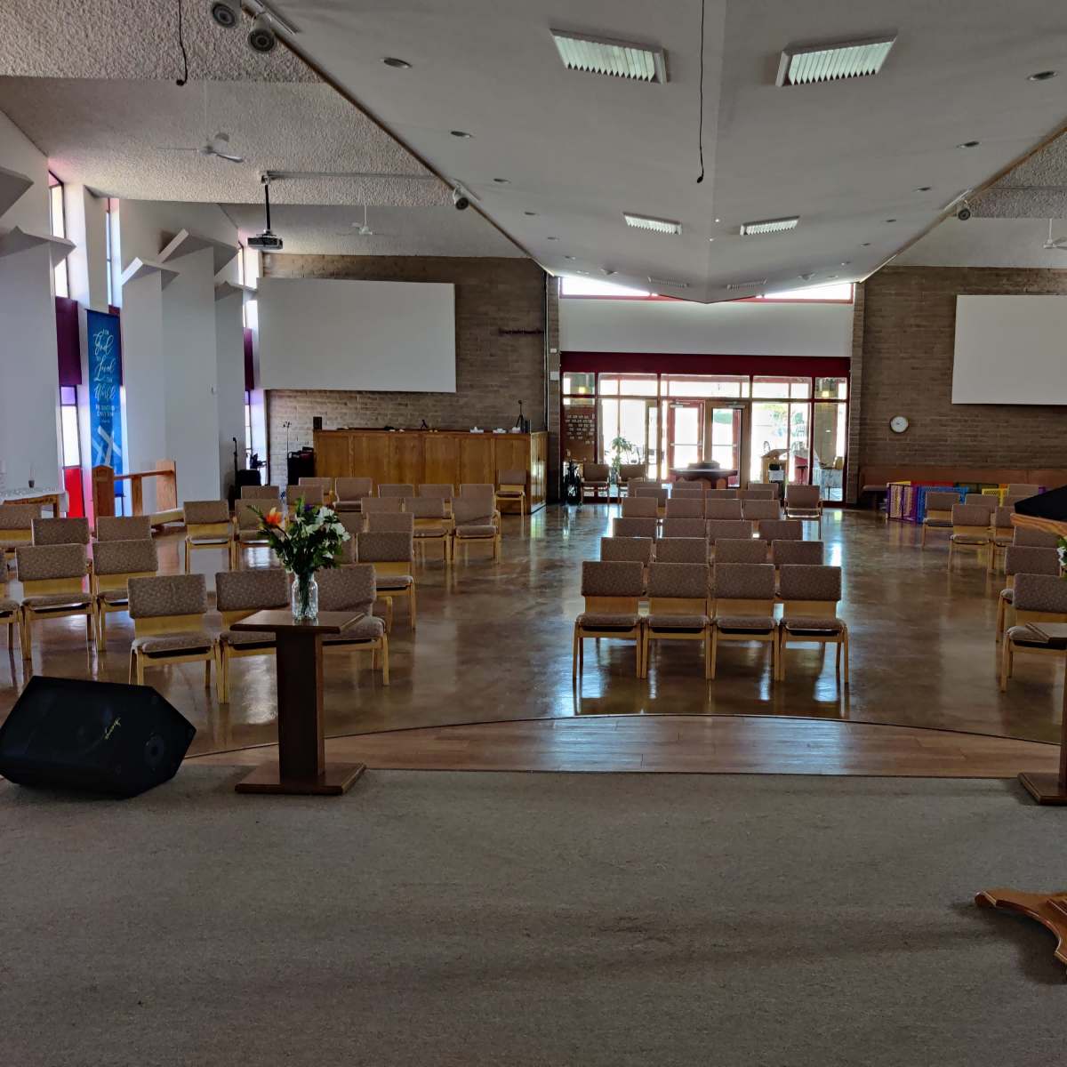 A spacious interior of a church with rows of chairs arranged facing a podium at the front.
