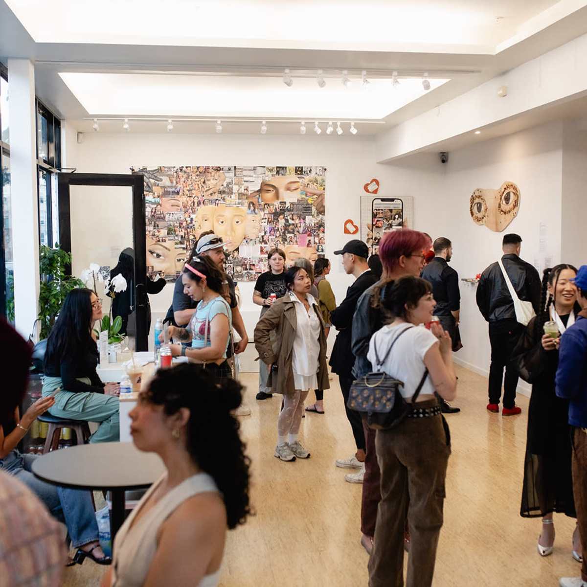 A lively art gallery with people socializing and engaging in conversation while surrounded by various artworks on the walls.