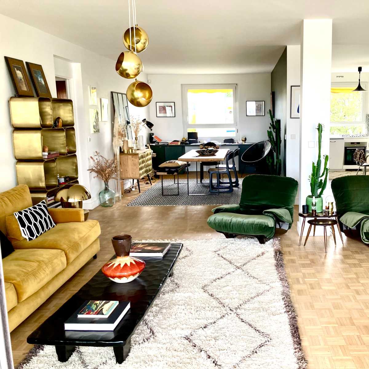 A modern living room featuring two green lounge chairs, a coffee table, a large area rug, and a dining area in the background.