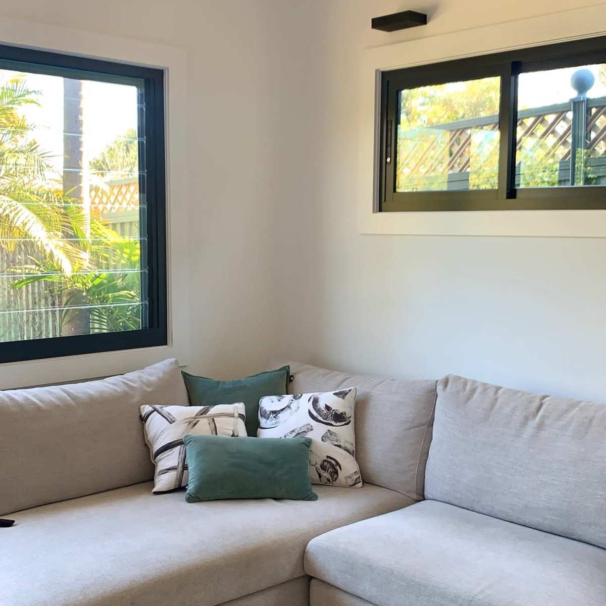 A light-colored sectional sofa in a bright room with large windows and decorative pillows on the cushions.