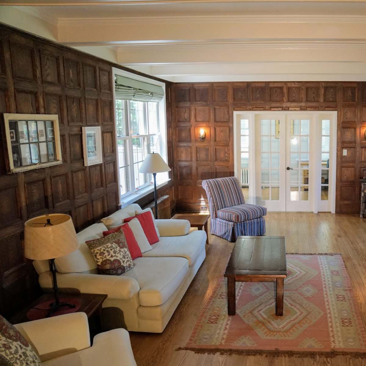 A living room with wooden paneled walls, a fireplace, a coffee table, and two sofas arranged around the space.