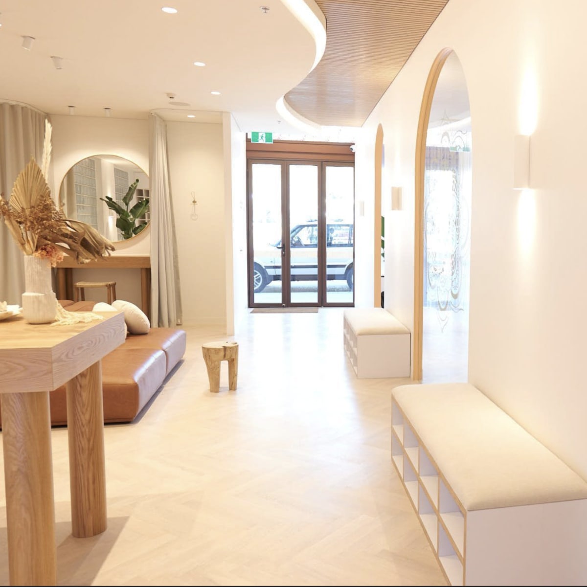 A modern, well-lit yoga studio with a minimalist interior, featuring a seating area, a large mirror, and yoga mats arranged on the floor.