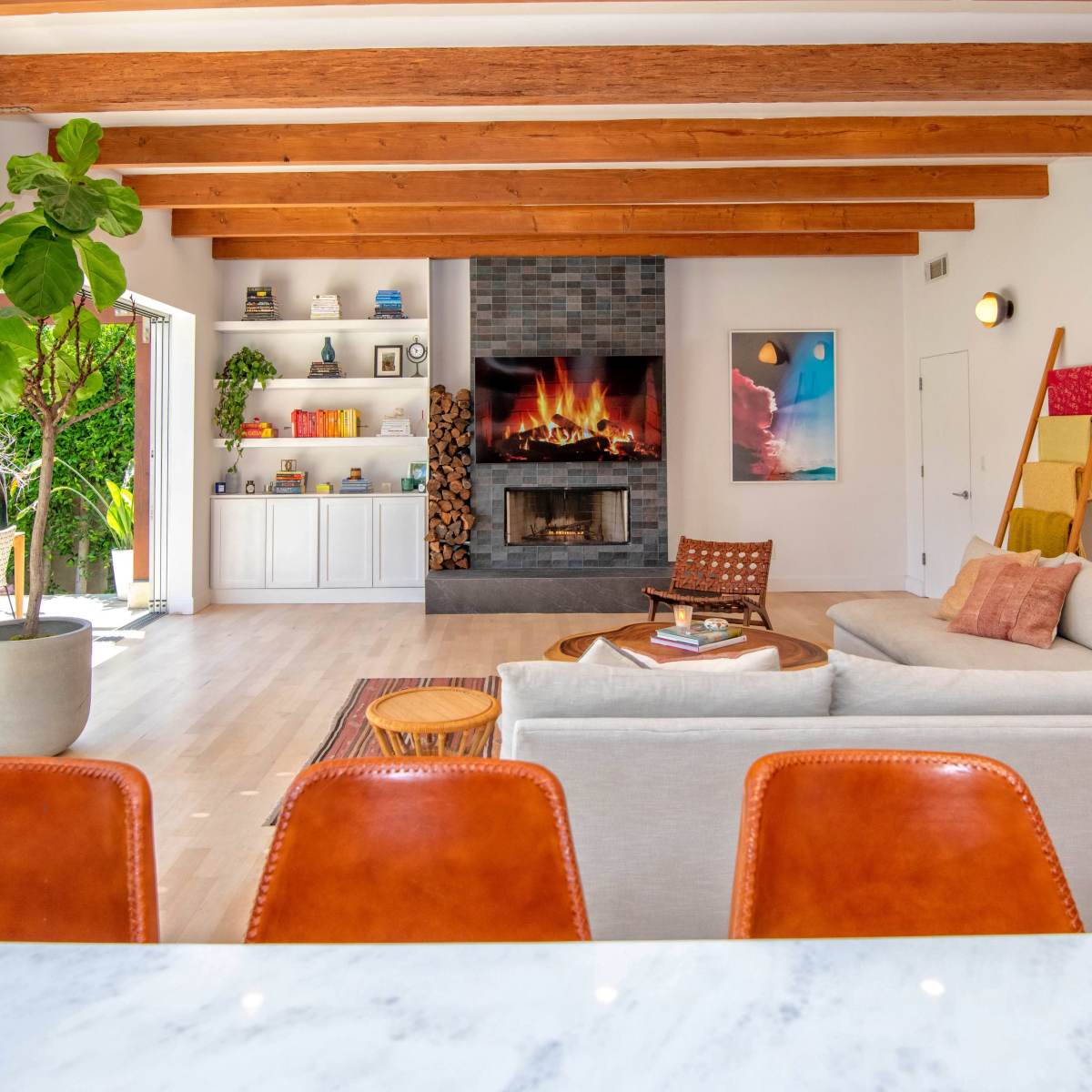 A modern living room with a central fireplace, wooden beams, and a spacious seating area.