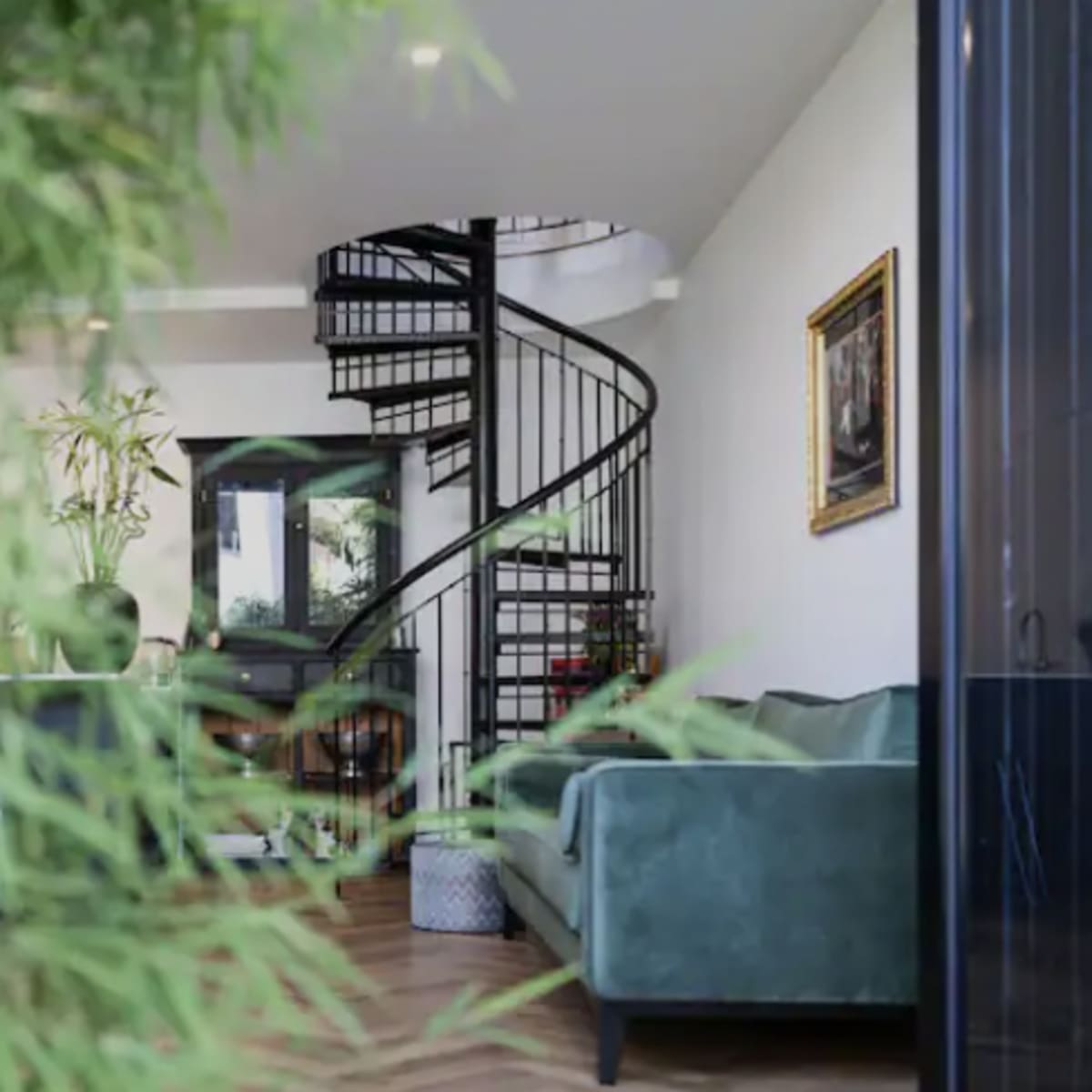 A modern interior featuring a spiral staircase, a green sofa, and decorative plants.