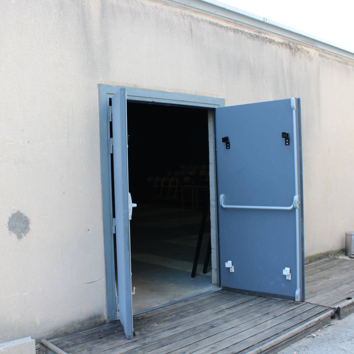 An open double door reveals a dark interior space with visible seating.