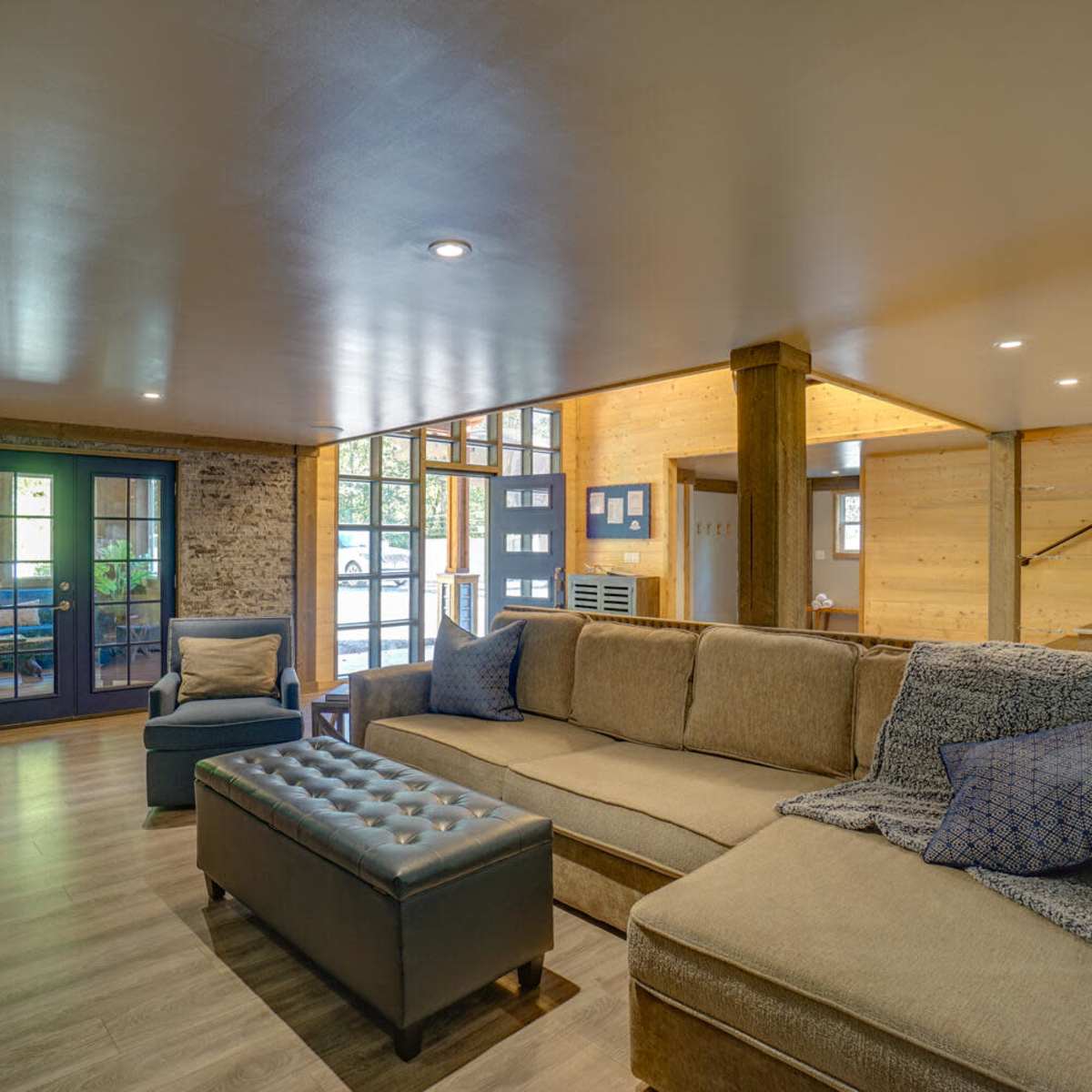 A spacious living room featuring a large sectional sofa, a coffee table, and large windows that allow natural light to fill the space.