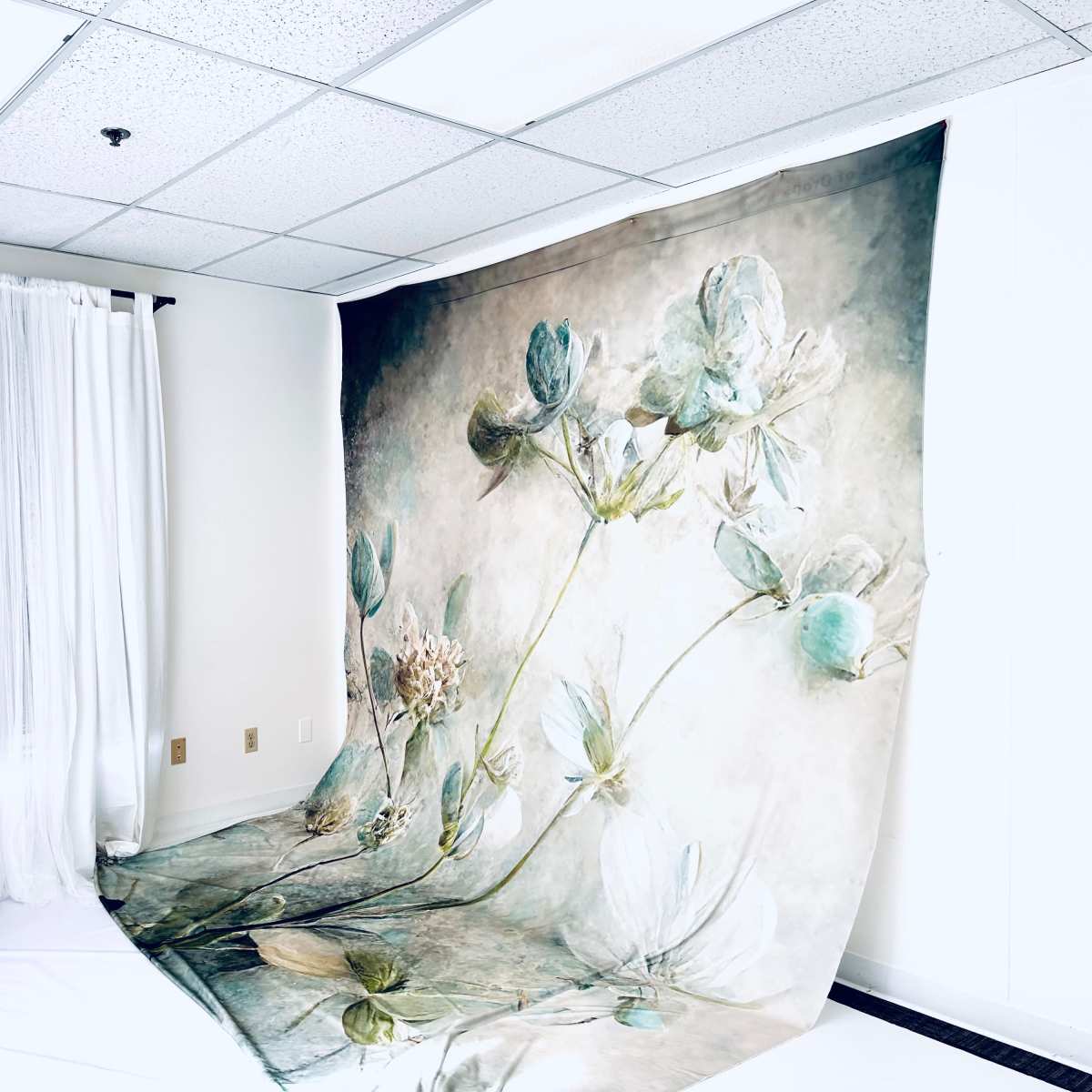 A large floral backdrop is displayed in a bright room with sheer curtains and a white floor.